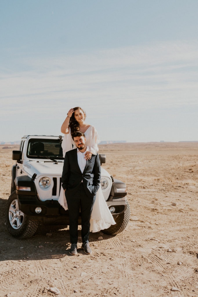 Bride and groom sitting on a jeep wrangler for their lake powell elopement