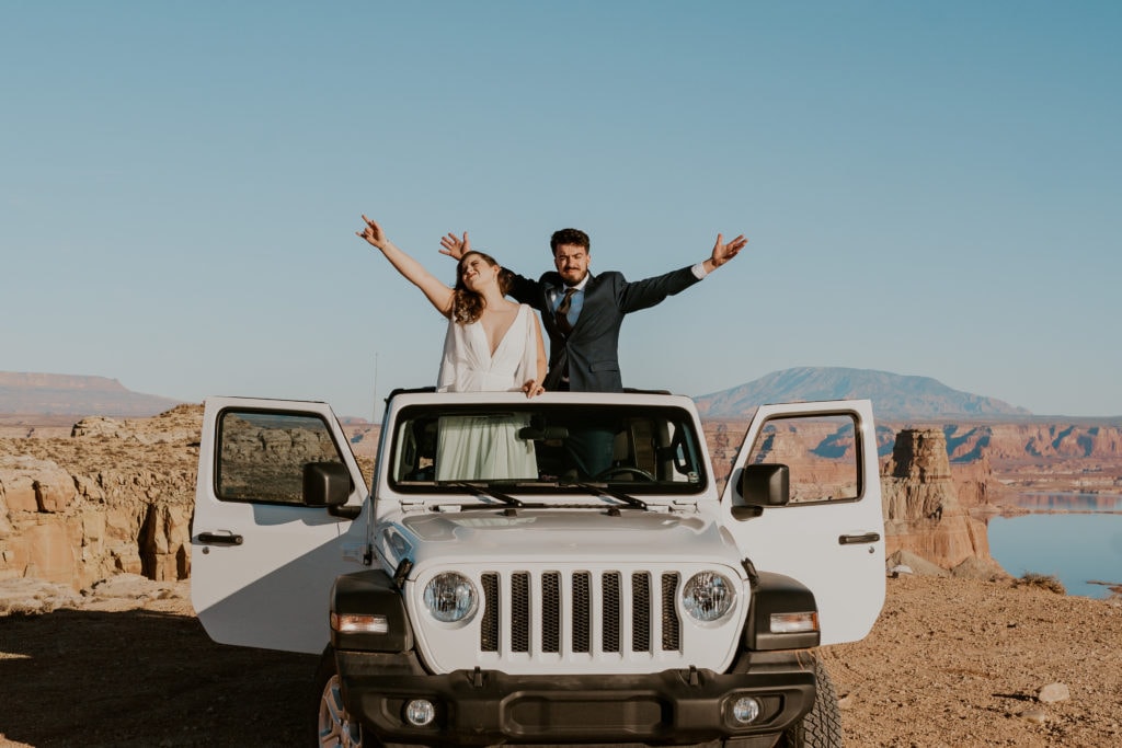 Bride and groom sitting on a jeep wrangler for their lake powell elopement