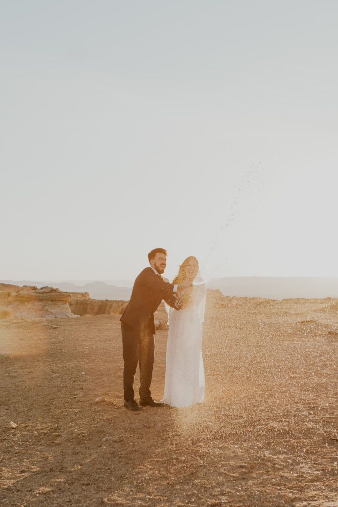 Bride and groom popping champaign after their lake powell elopement